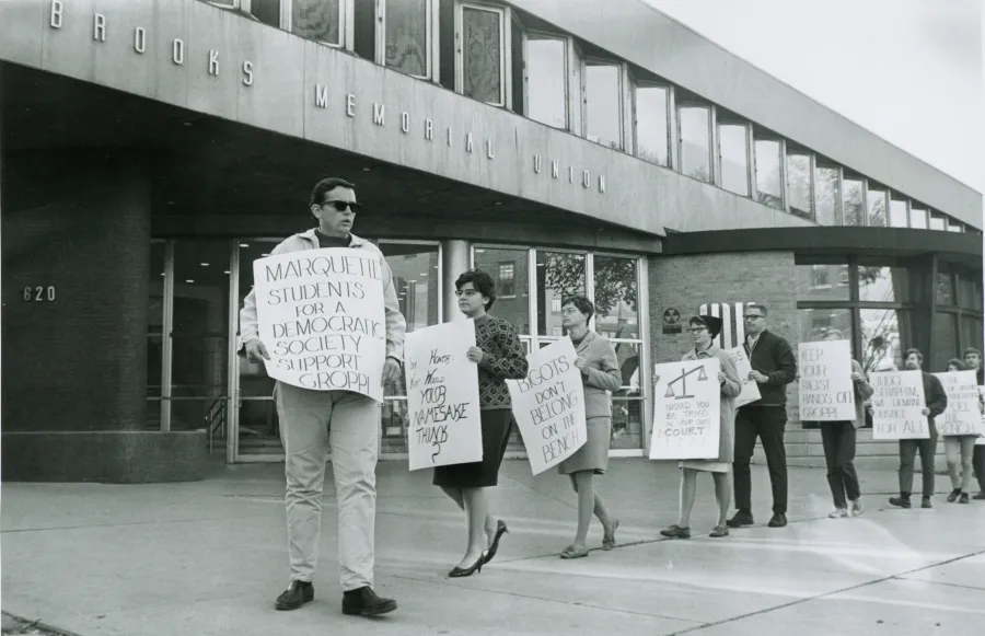 Students United for Racial Equality (SURE) protest at a speech by Judge Christ T. Seraphim outside of Brooks Memorial Union at Marquette University. Judge Seraphim was frequently picketed due to his refusal to quit the then-segregated Eagles Club.